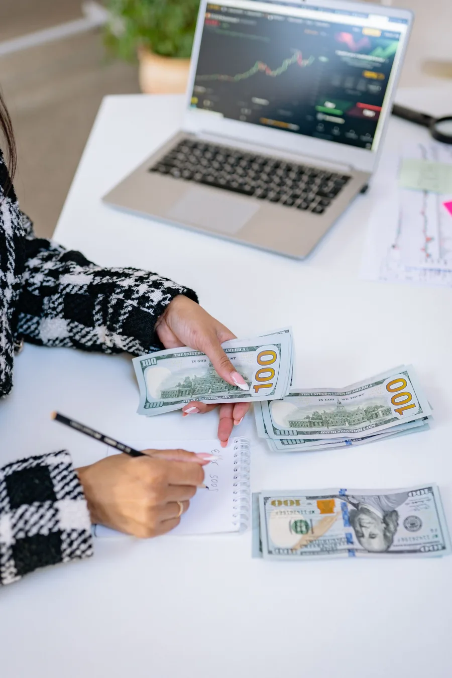 Client planning finances beside a laptop and cash notes
